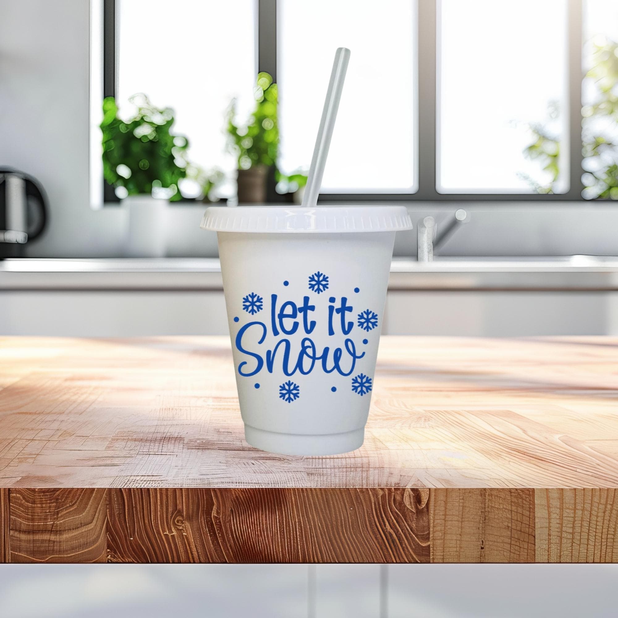 White cup with 'let it snow' text on a wooden surface